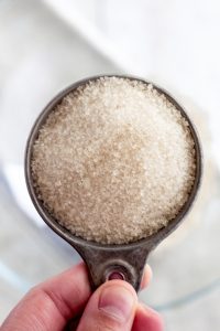 adding cane sugar to a bowl for The best white peach strawberry bars