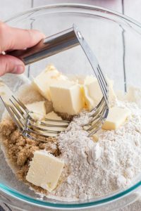 Using a pastry blender to mix butter into our dry mix for The best white peach strawberry bars