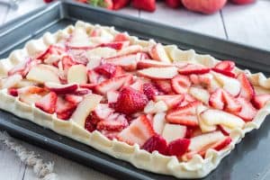 a white peach strawberry tart/bar on a sheet pan ready to go into the oven