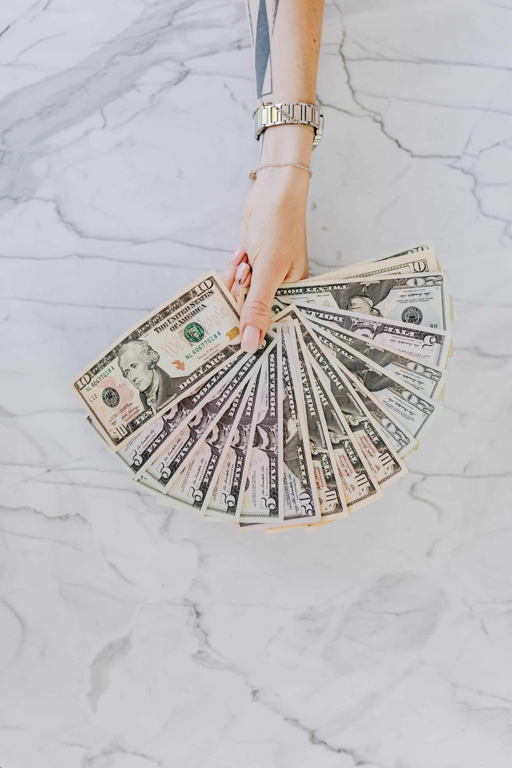 9 ways to keep your money safe; picture of a woman's hand with lots of American dollars fanned out