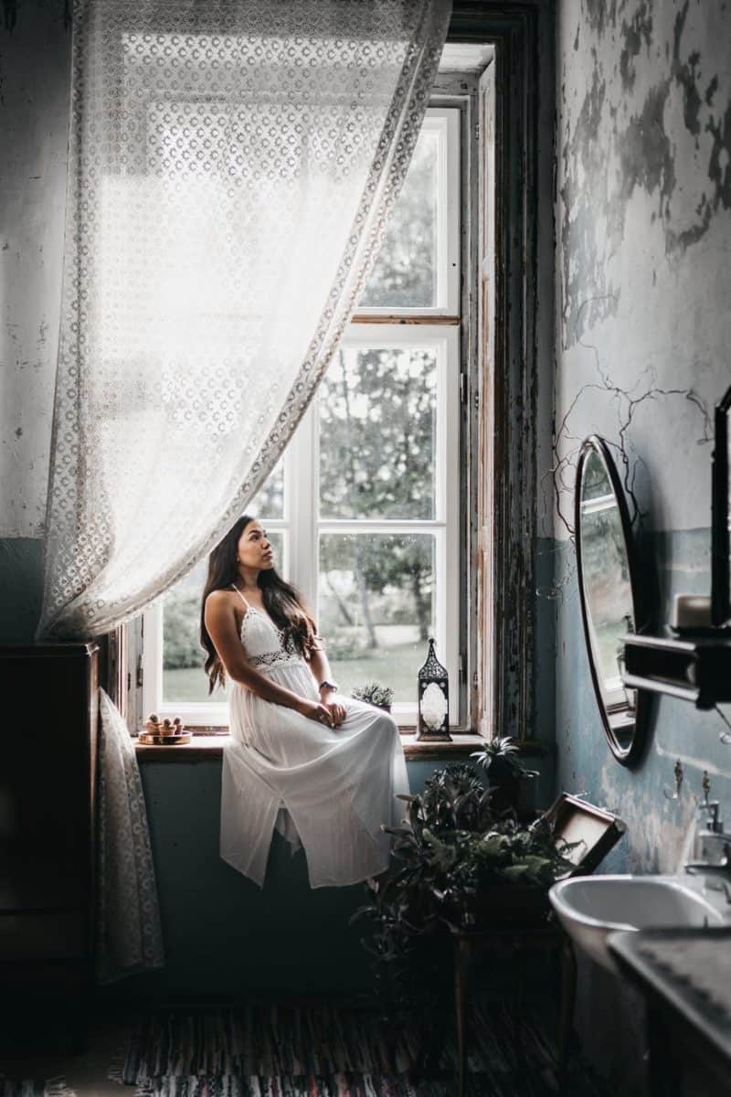 charming woman resting on windowsill in shabby bathroom