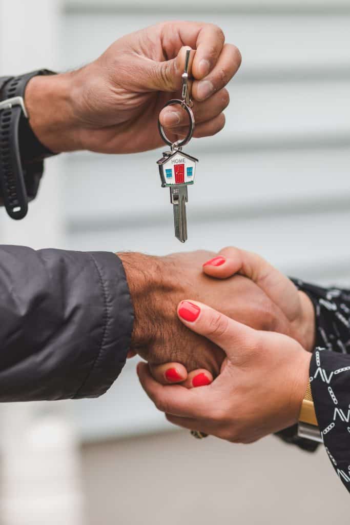 how to prepare to sell your house; two hands hold a man's hand while his other hand holds up a key