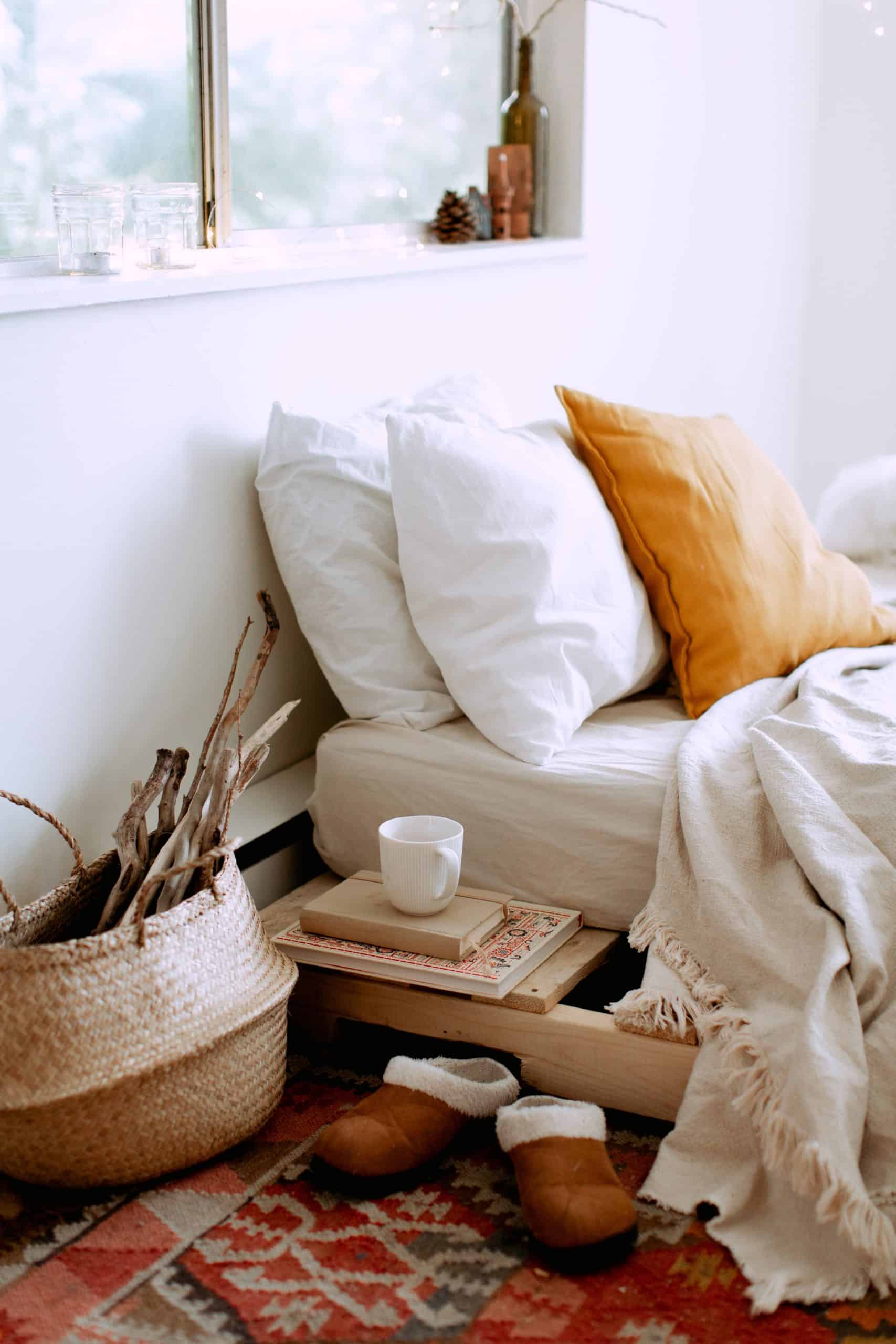 Cozy bedroom; picture of a bed with big pillows, a nightstand, and a basket