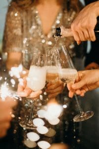 How to entertain guests at home; person pouring champagne on champagne flutes