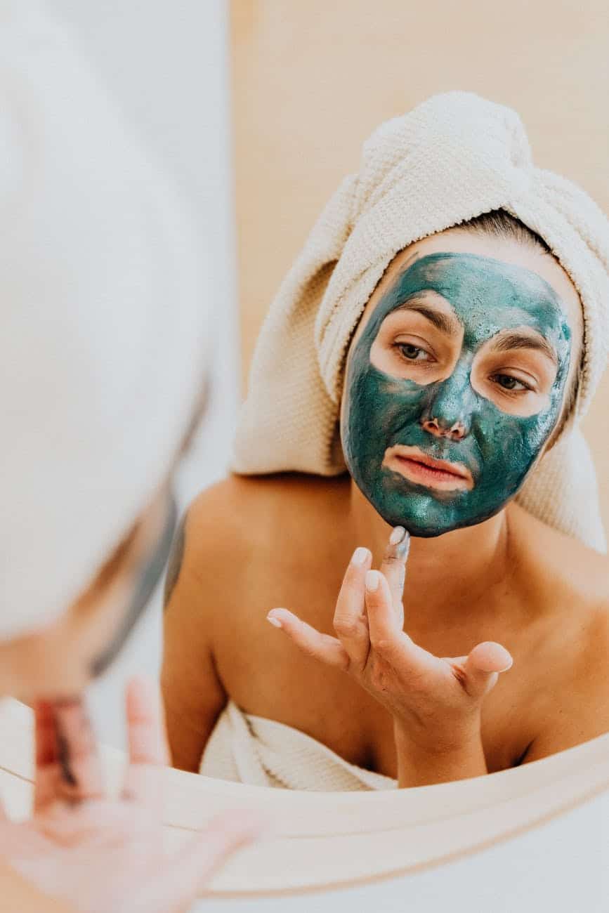 woman applying a green facial mask