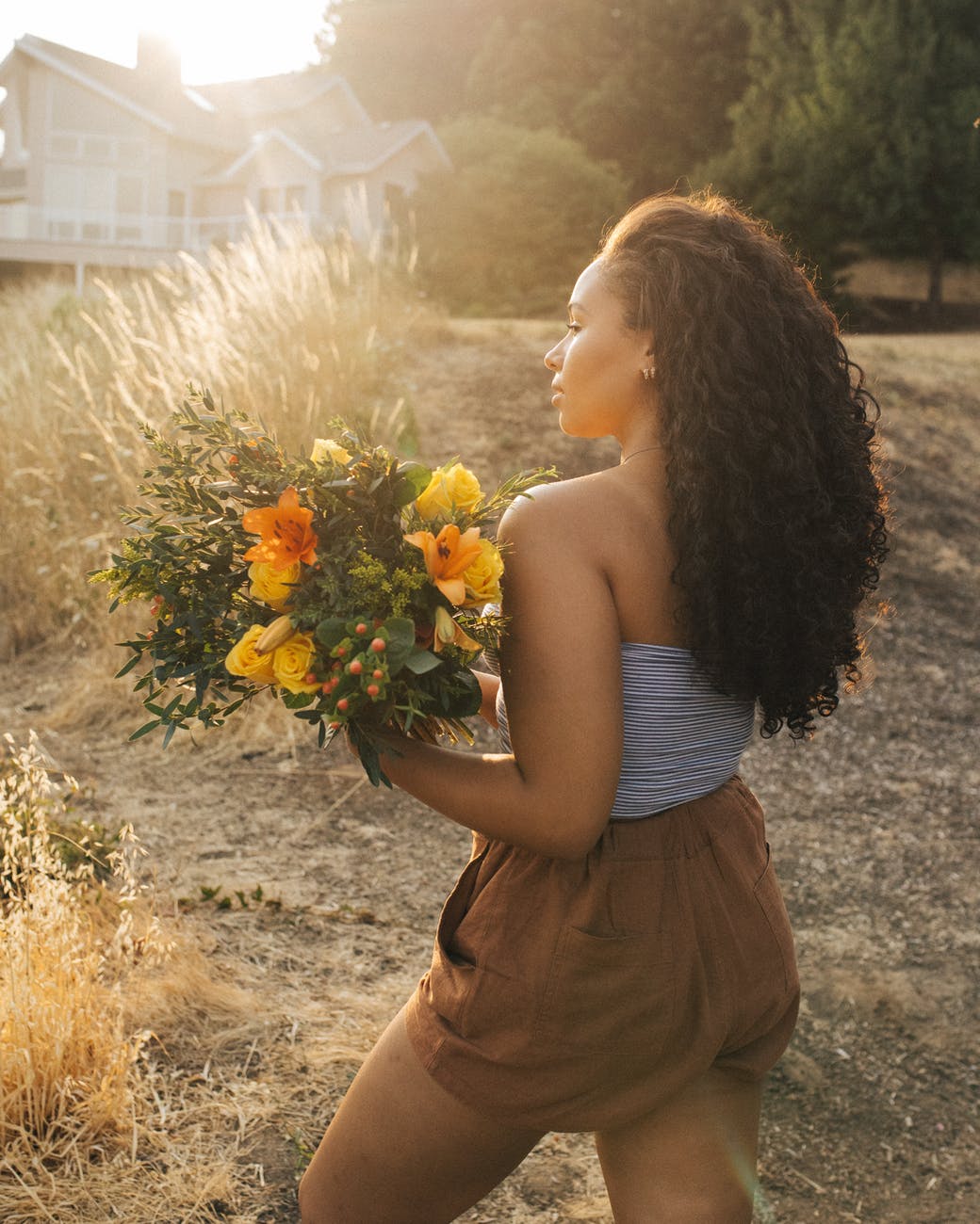 woman in gray off shoulder top and brown shorts holding yellow flower