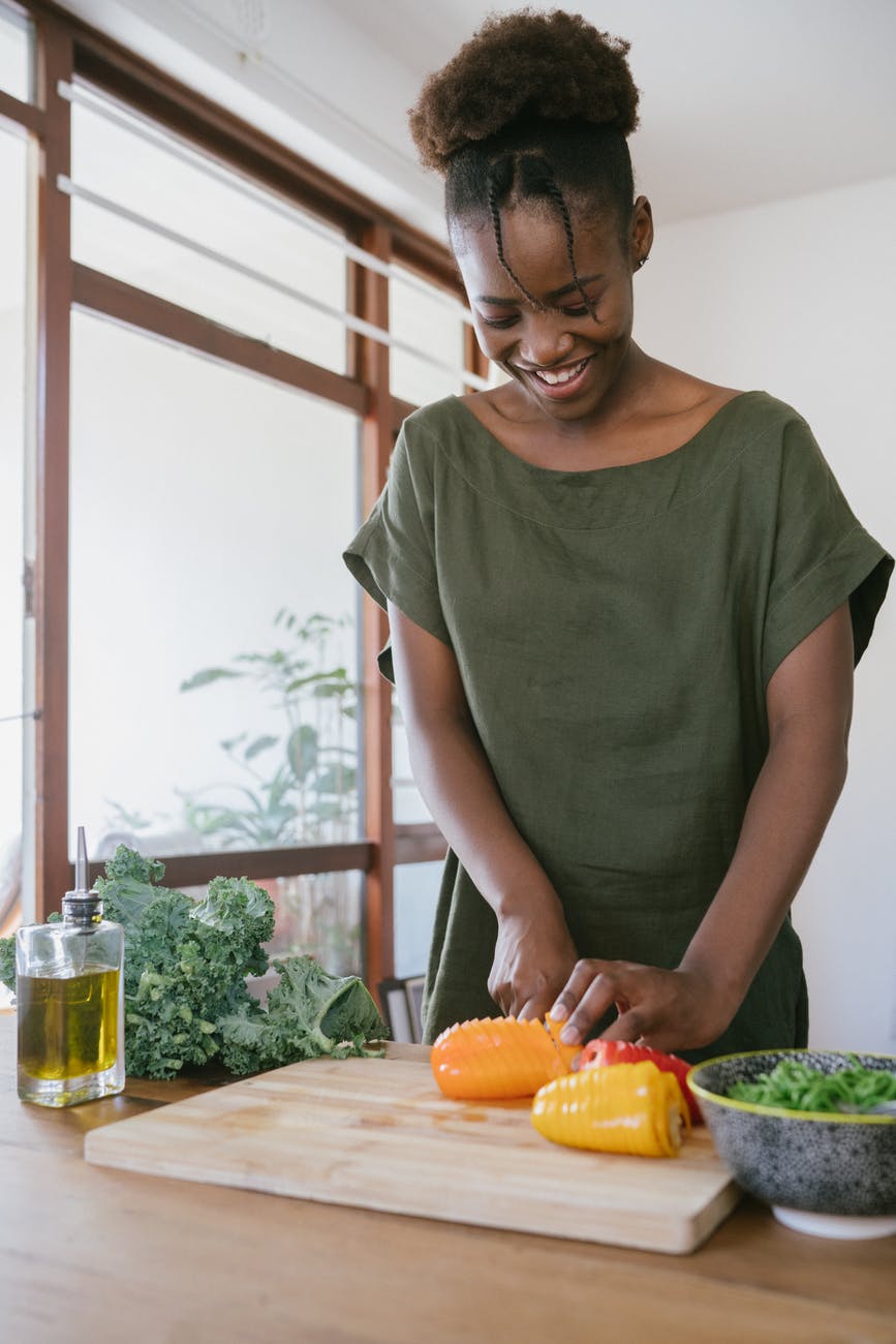 woman in green tank top holding orange bell pepper