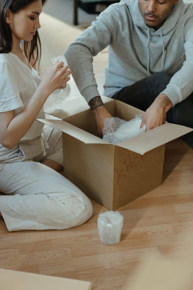 woman in gray long sleeve shirt and white pants sitting on brown wooden table