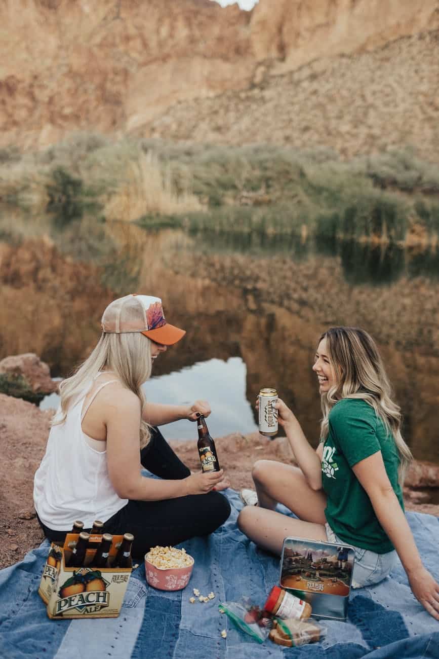 woman in green crew neck t shirt sitting beside woman in white top on picnic