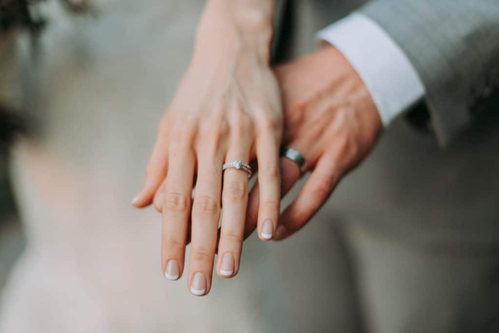 couple holding hands; wedding ring metals