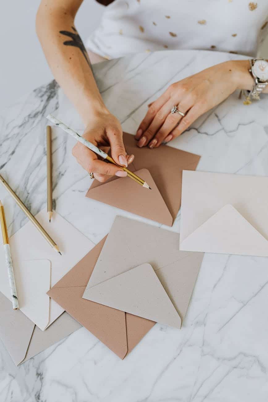 person holding a pencil and writing on an envelope