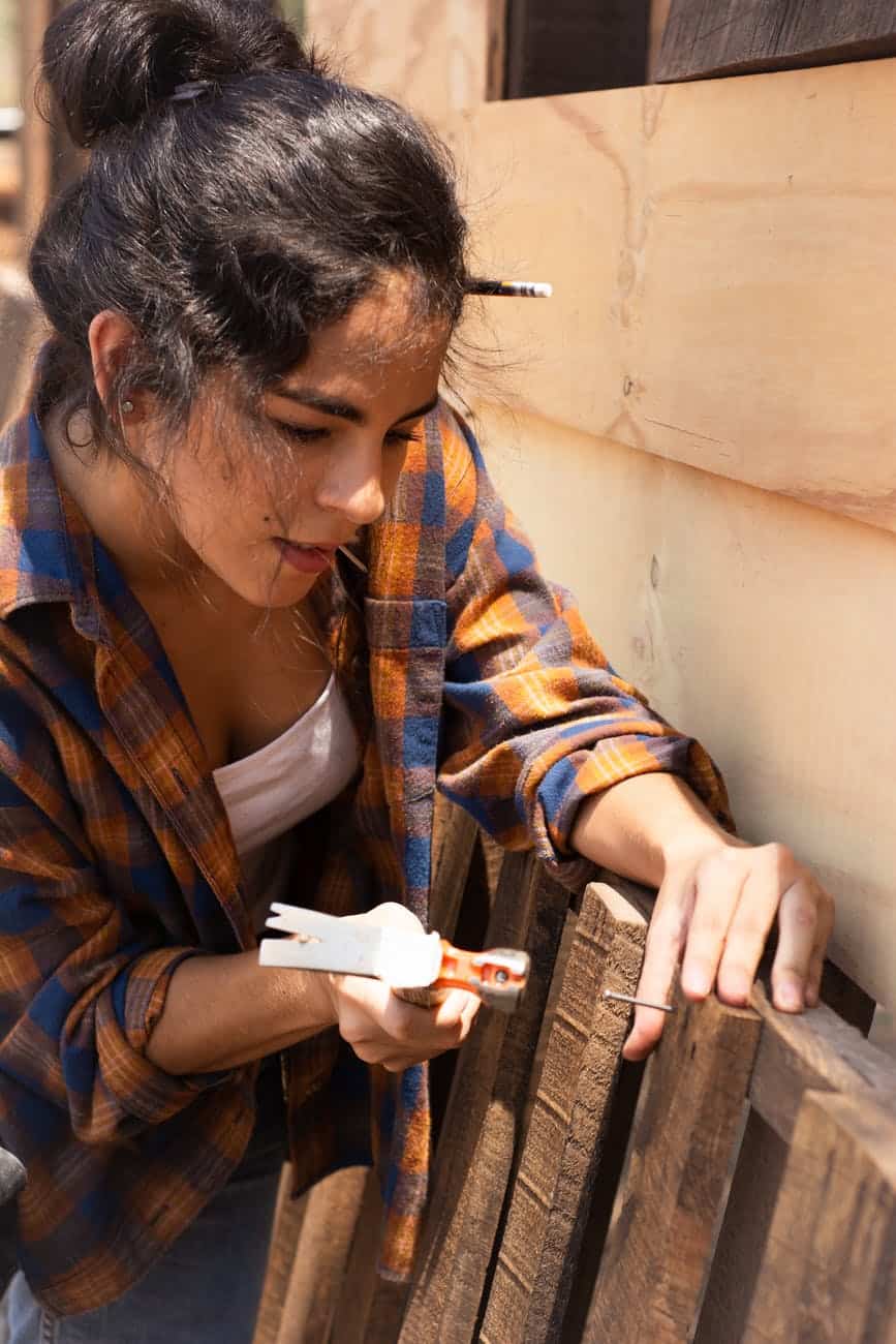 woman hammering a nail to a wood plank