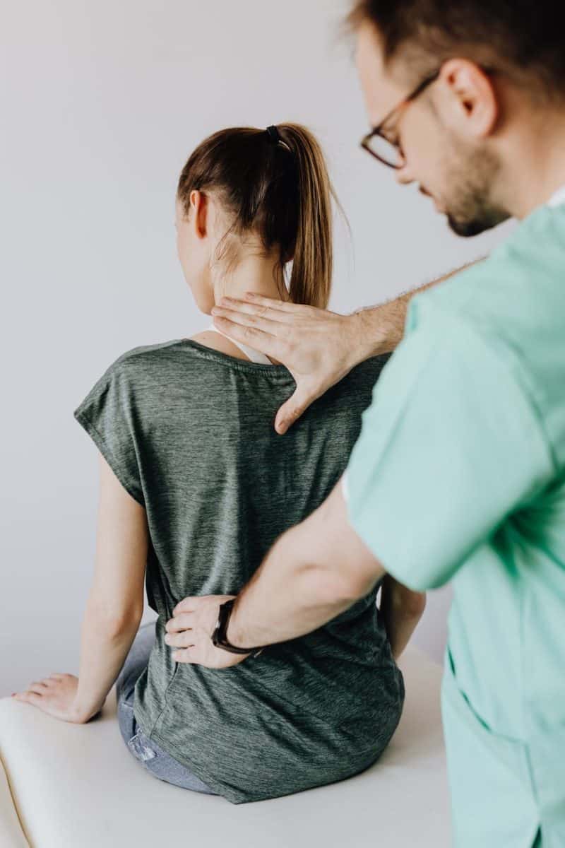 crop osteopath checking up back of anonymous patient in hospital