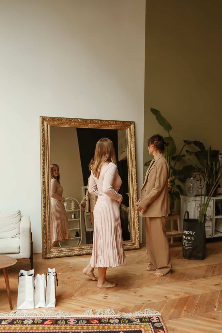 women fitting clothes in front of a mirror