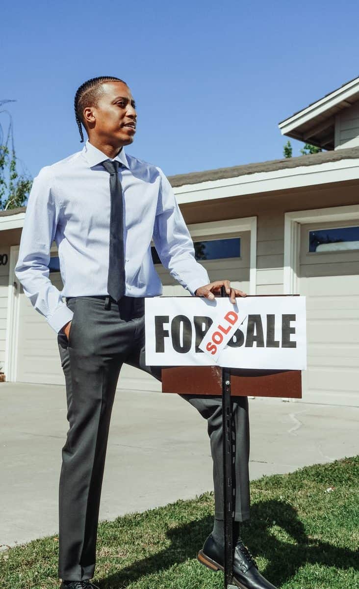 man in blue dress shirt holding a sold sign