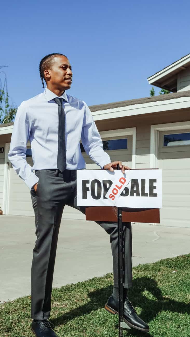 man in blue dress shirt holding a sold sign