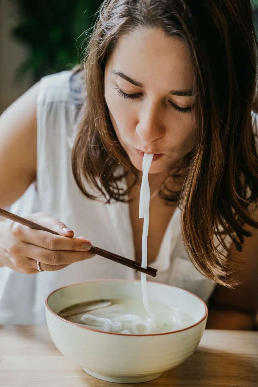 a woman eating noodle soup with chopsticks