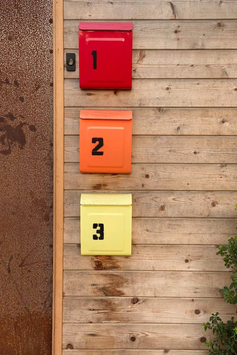 colorful mailboxes on wooden wall near door and plant