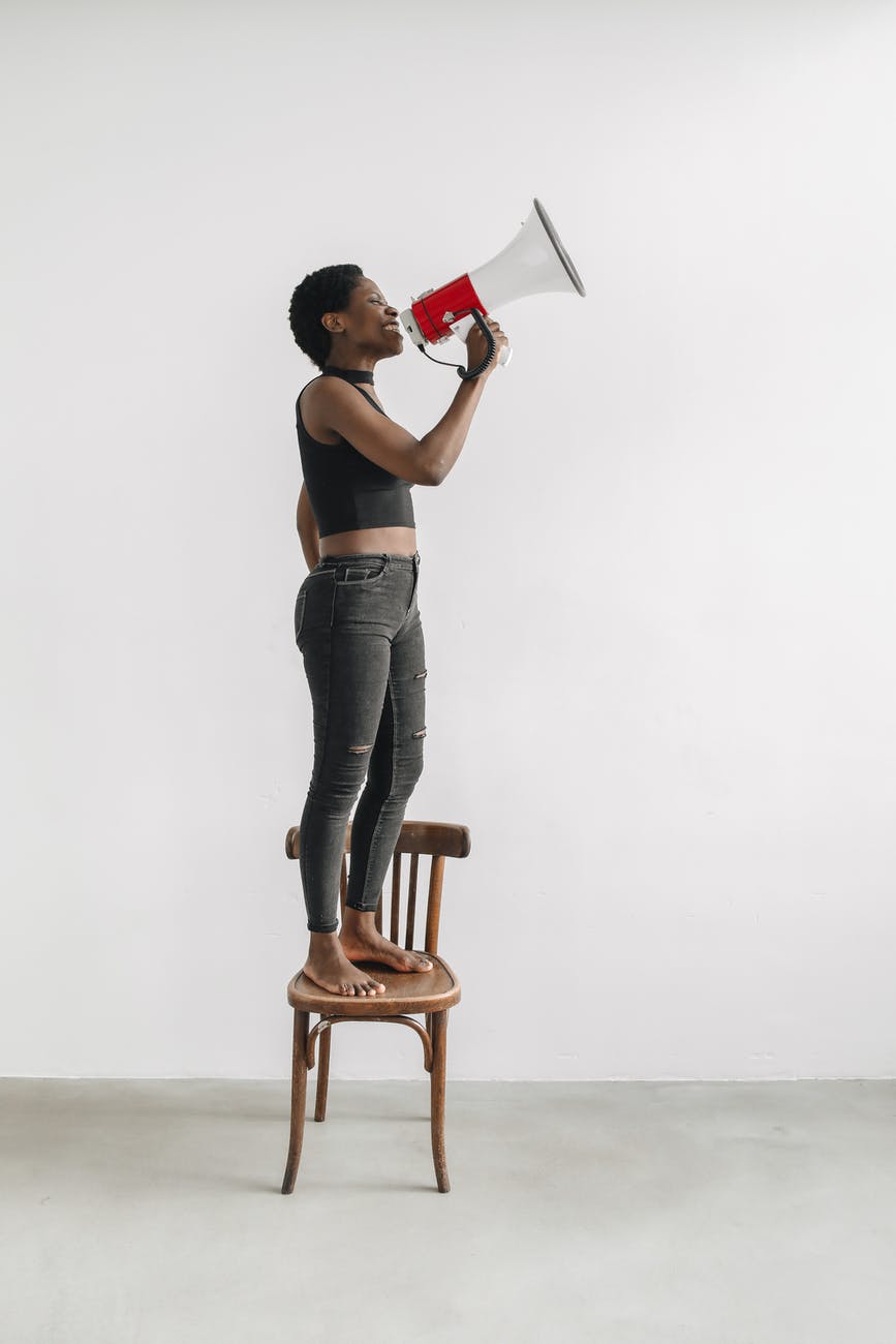 woman protesting through a megaphone while standing on a chair
