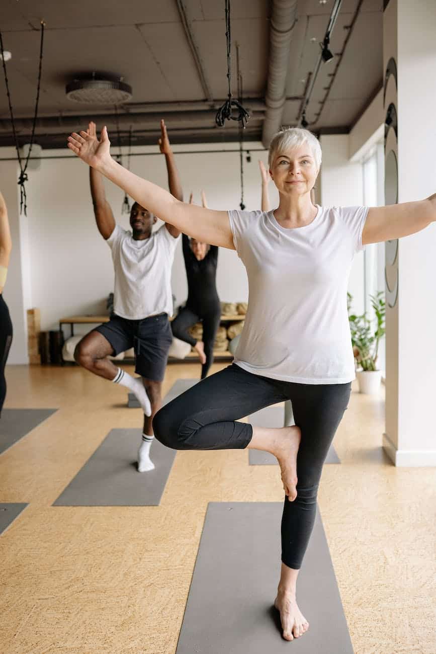 elderly woman in white shirt doing yoga