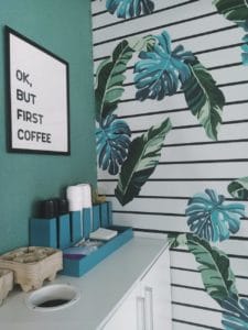 wooden cabinet beside the wall with leaves wallpaper