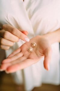 close up photo of person holding earrings
