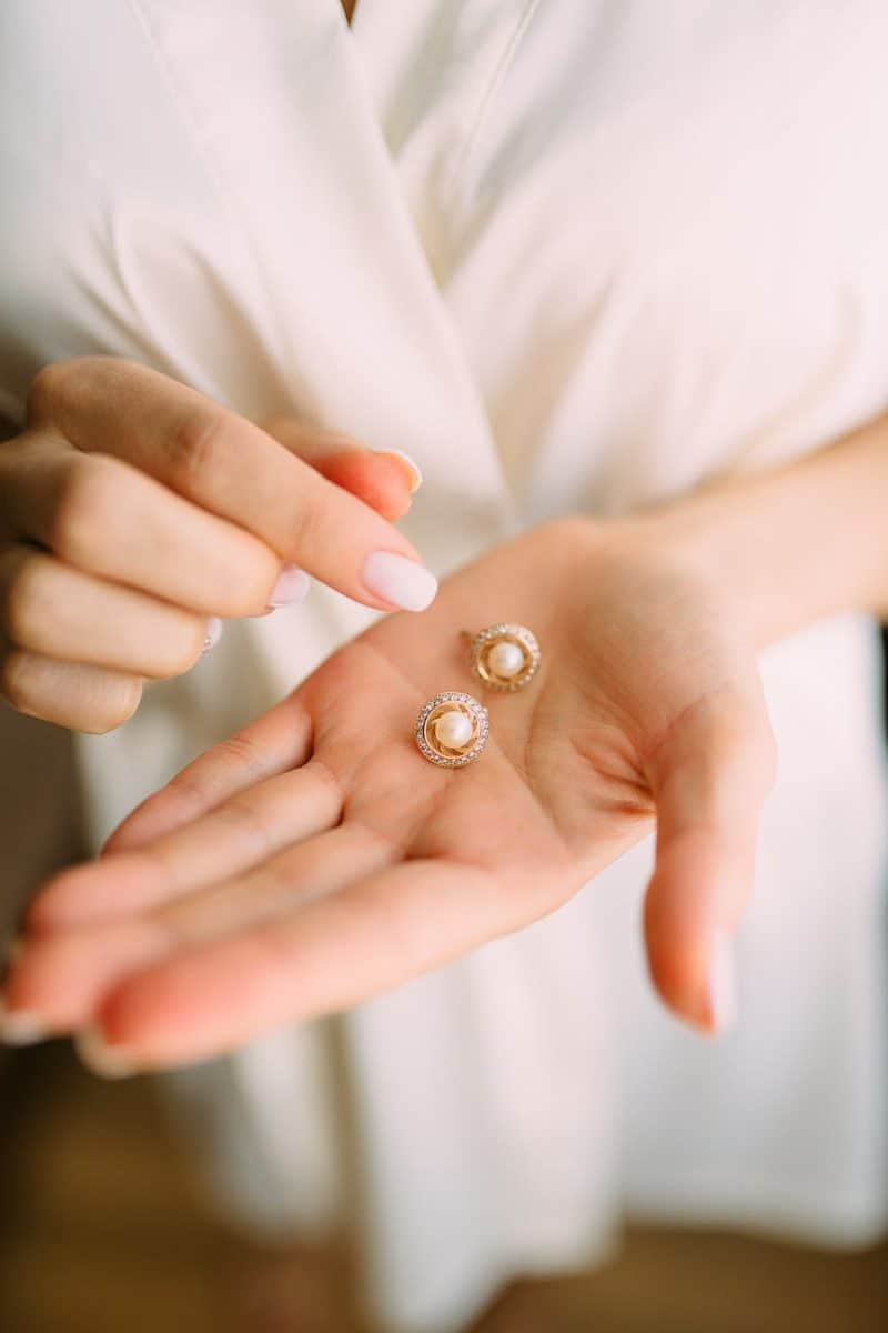 close up photo of person holding earrings