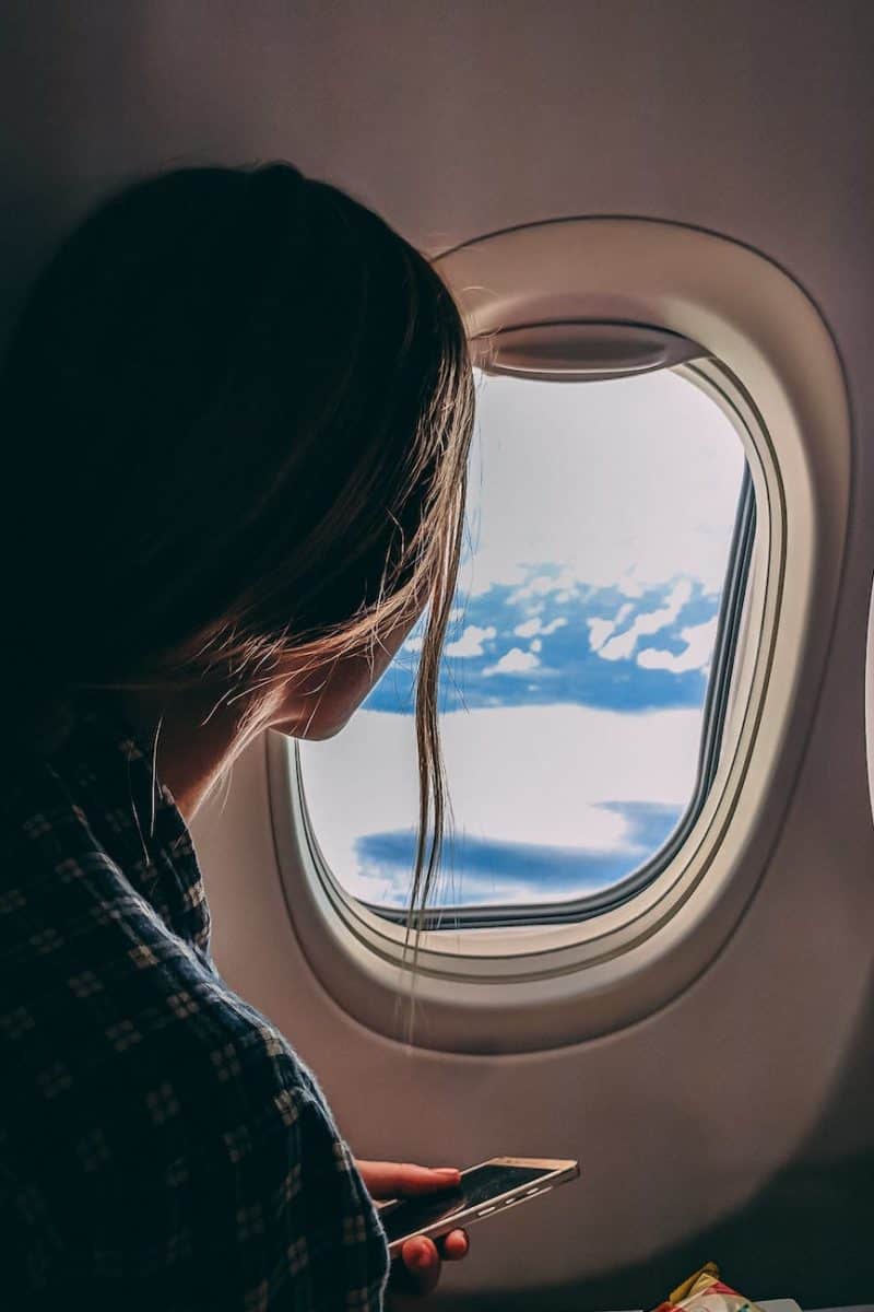 person holding smartphone riding airplane