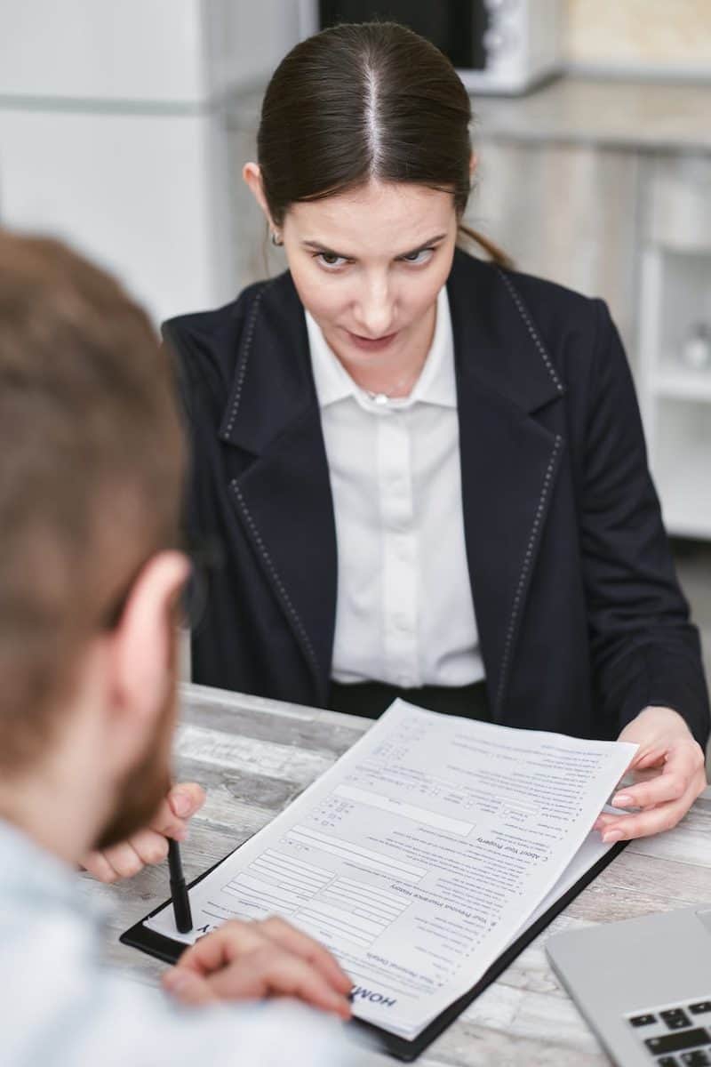 a woman holding a document talking to a man across the desk