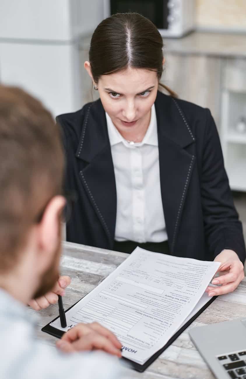 a woman holding a document talking to a man across the desk
