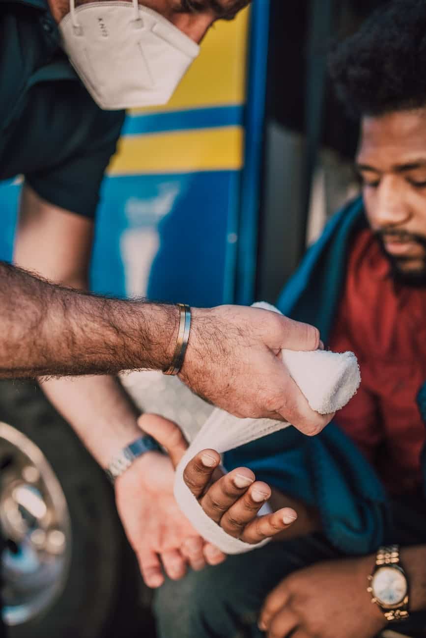 paramedic putting bandage on man s hand