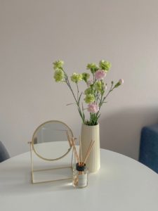 round mirror near a flower vase