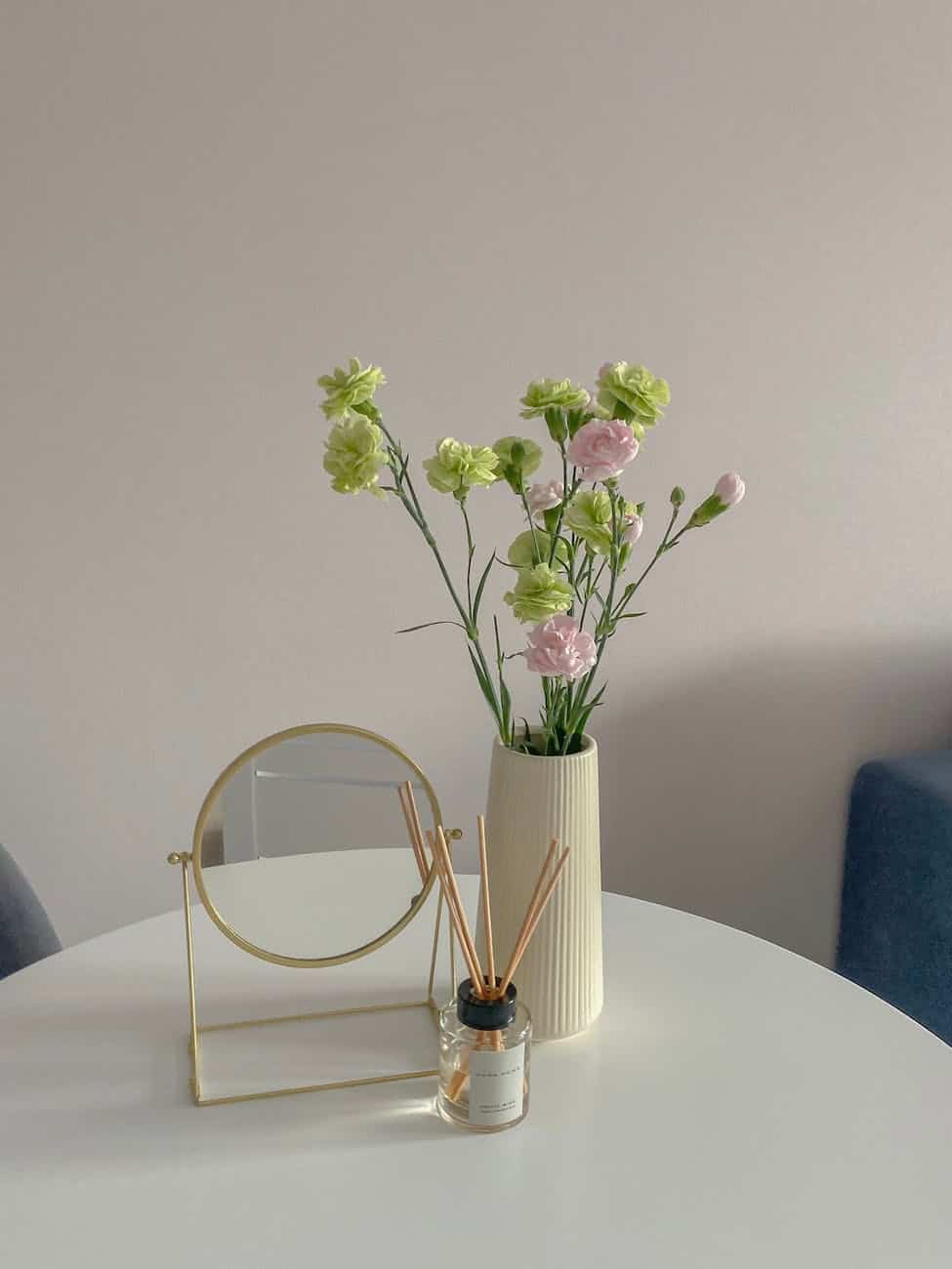 round mirror near a flower vase