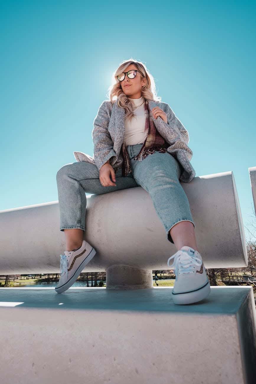 woman in denim jeans sitting on concrete bench