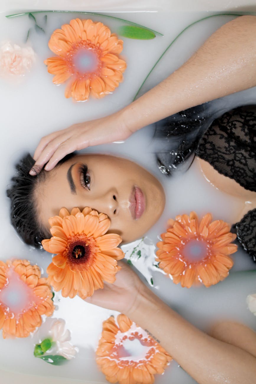 woman lying in bathtub with orange petaled flowers