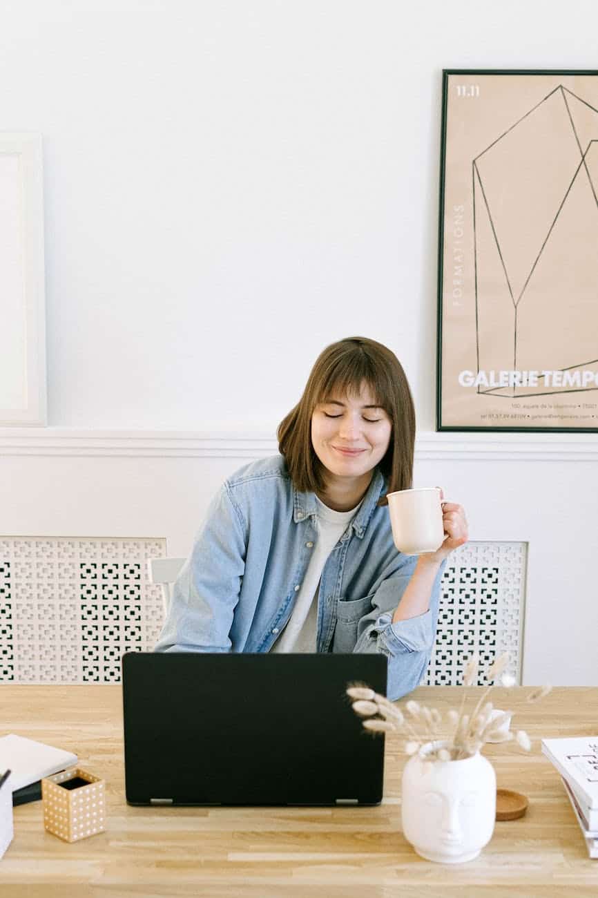 woman drinking coffee and looking at a laptop