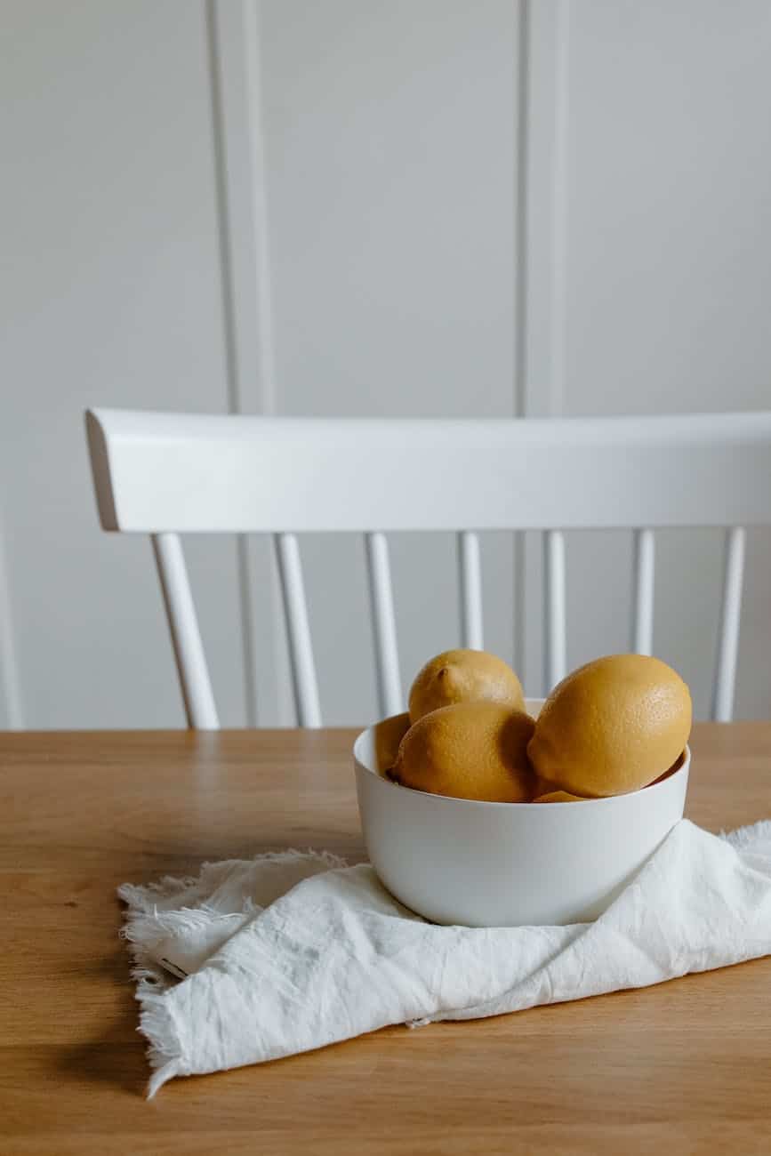 bowl filled with lemons on textile on table near chair