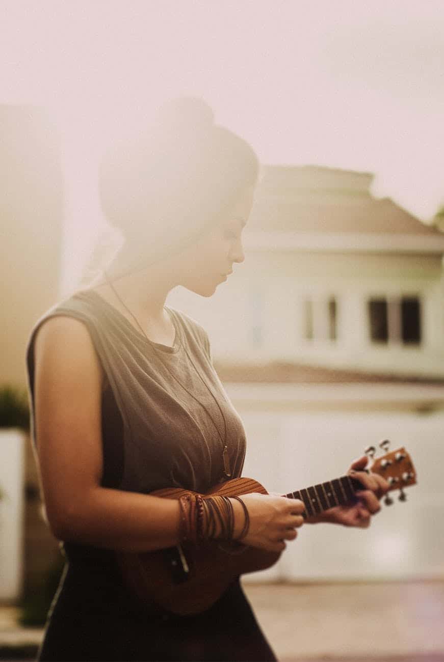 woman in brown sleeveless dress while playing ukulele