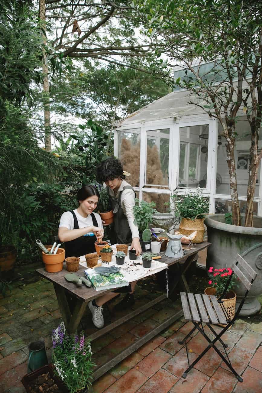 female gardeners working in floral garden with potted plants