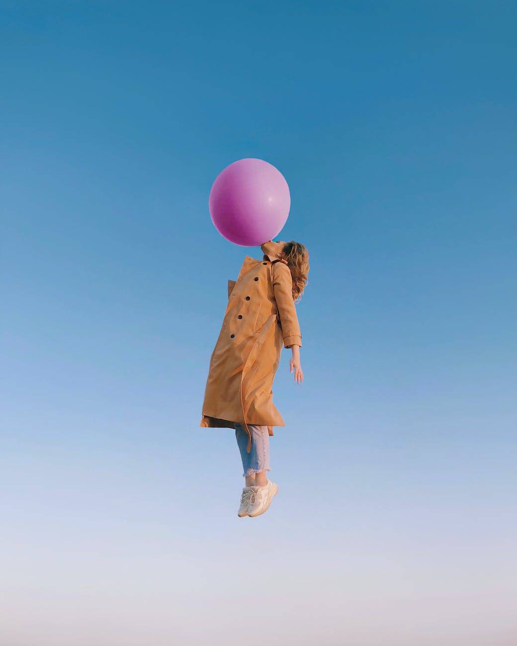 young female blowing huge balloon in sky