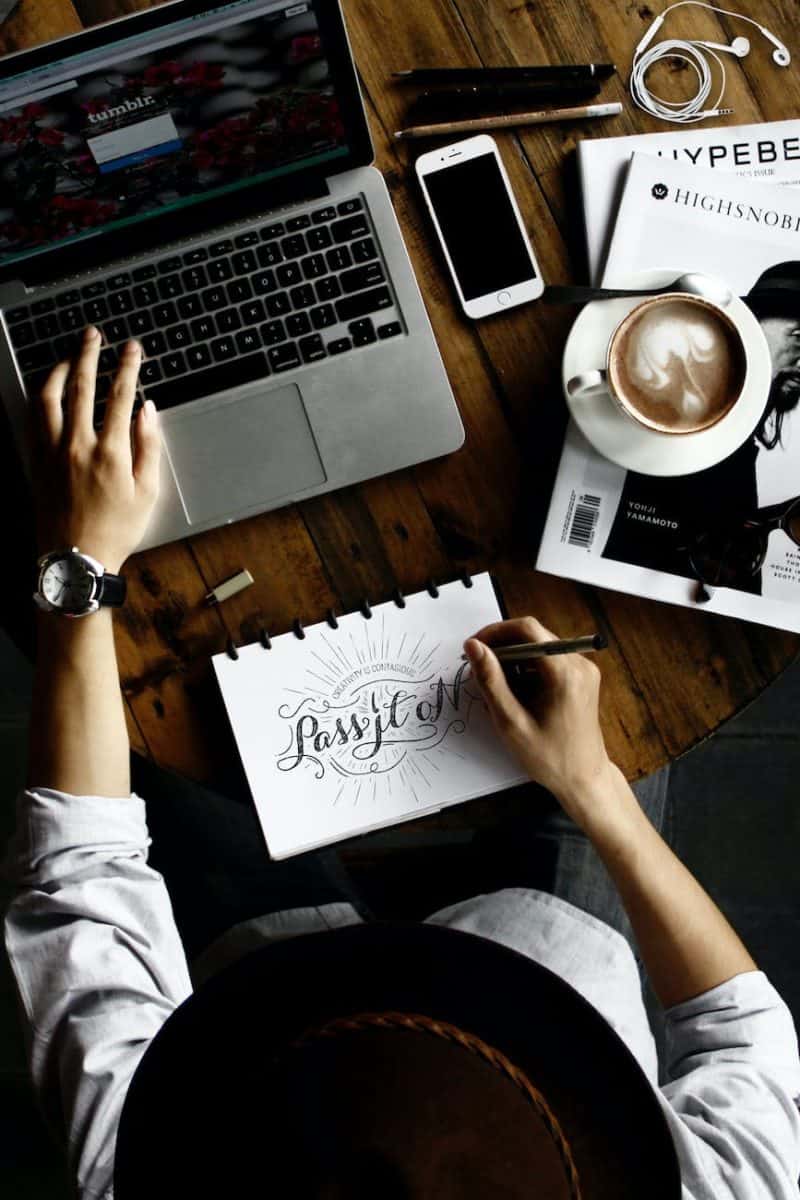 person sitting facing laptop computer with sketch pad