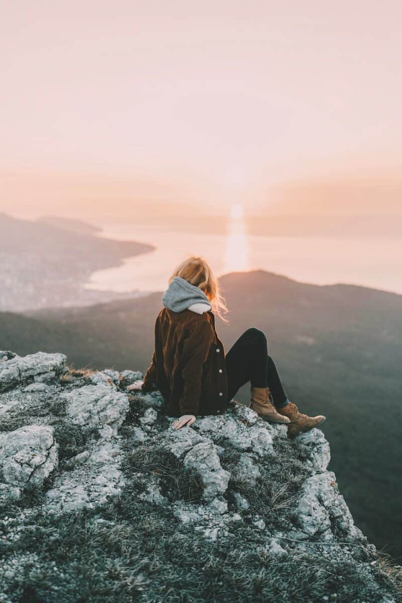 photo of woman sitting on rock
