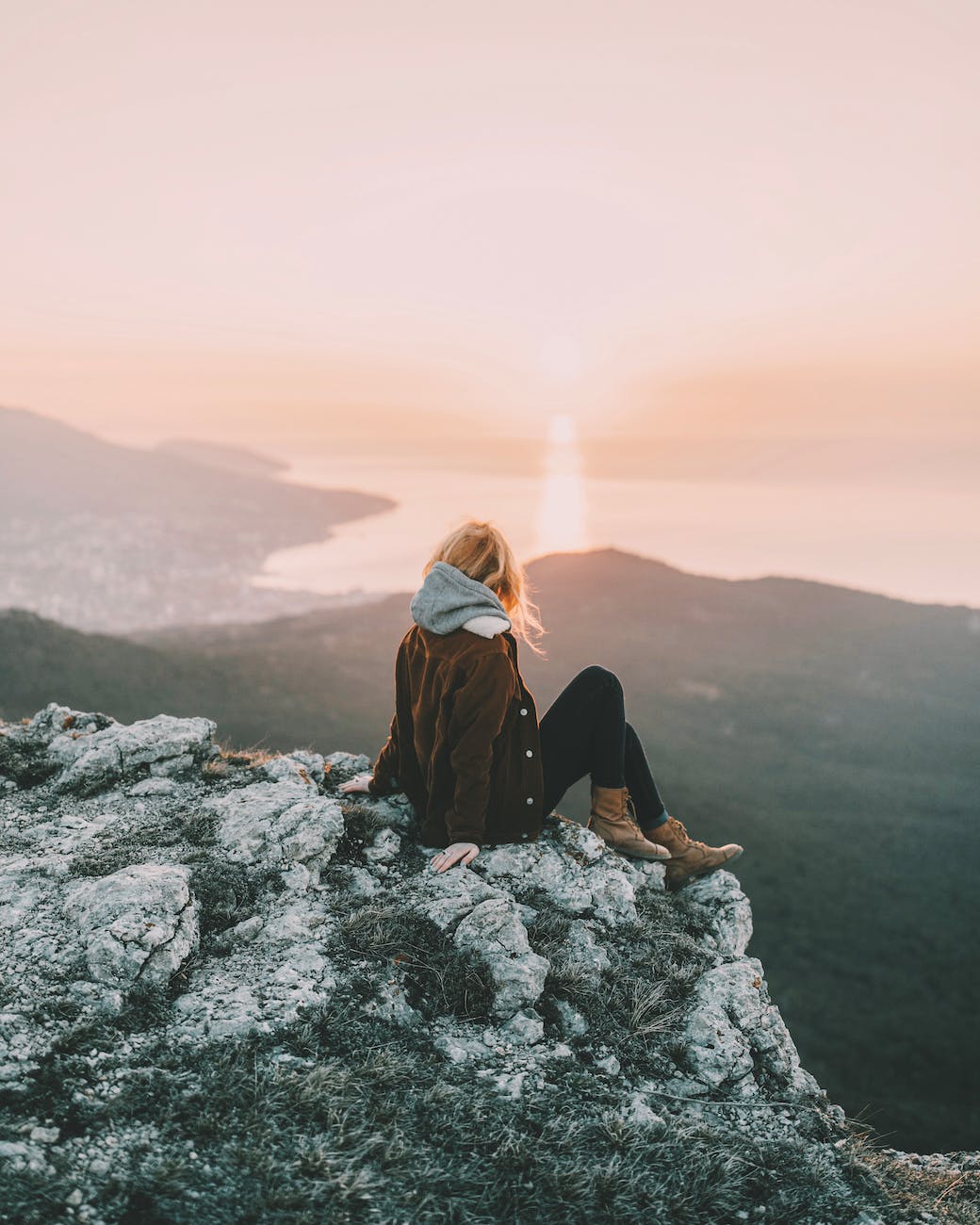 photo of woman sitting on rock