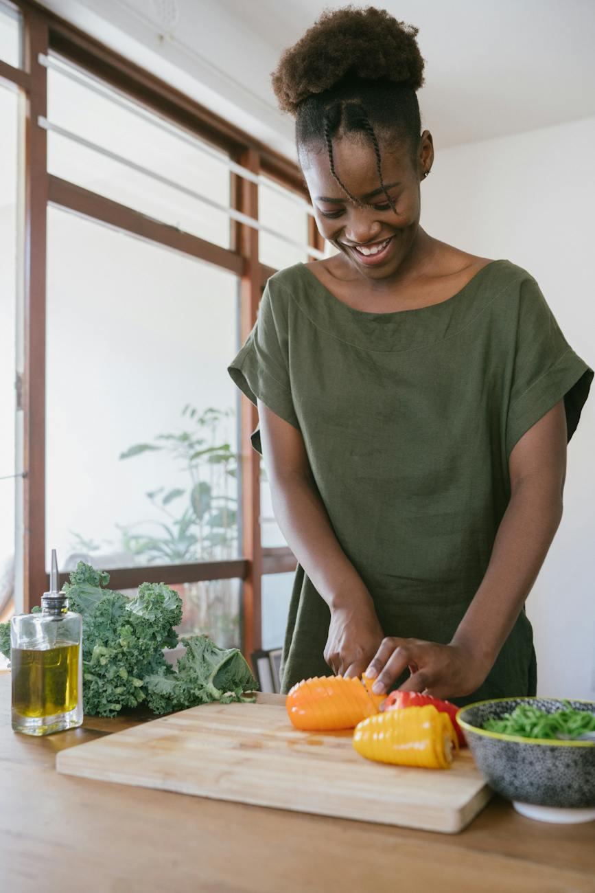 woman in green tank top holding orange bell pepper