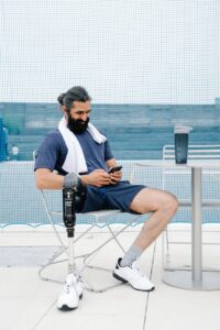 man with prosthetic limb sitting on a chair while happily looking at phone