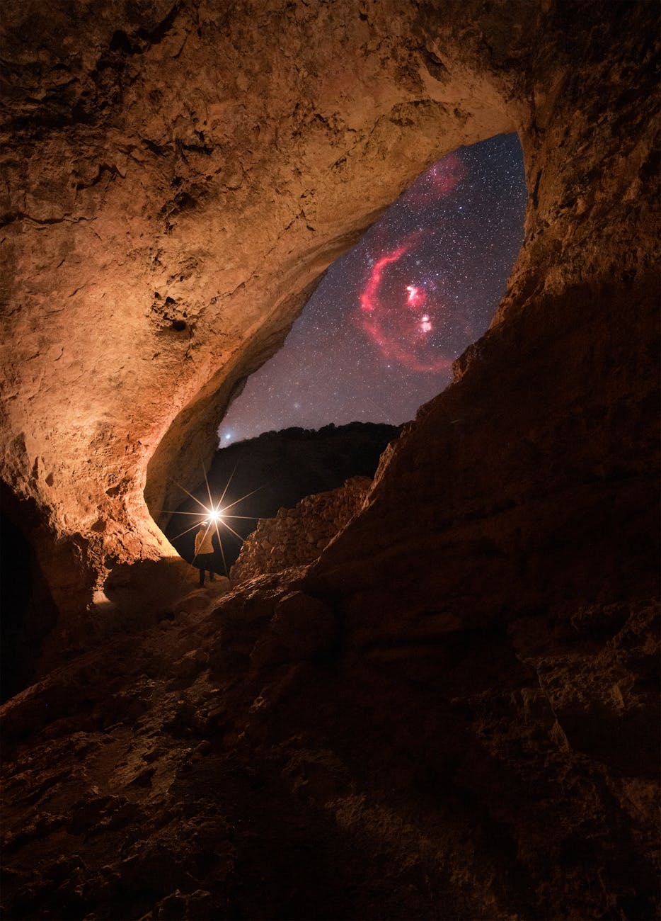 person walking with flashlight among rocks at night