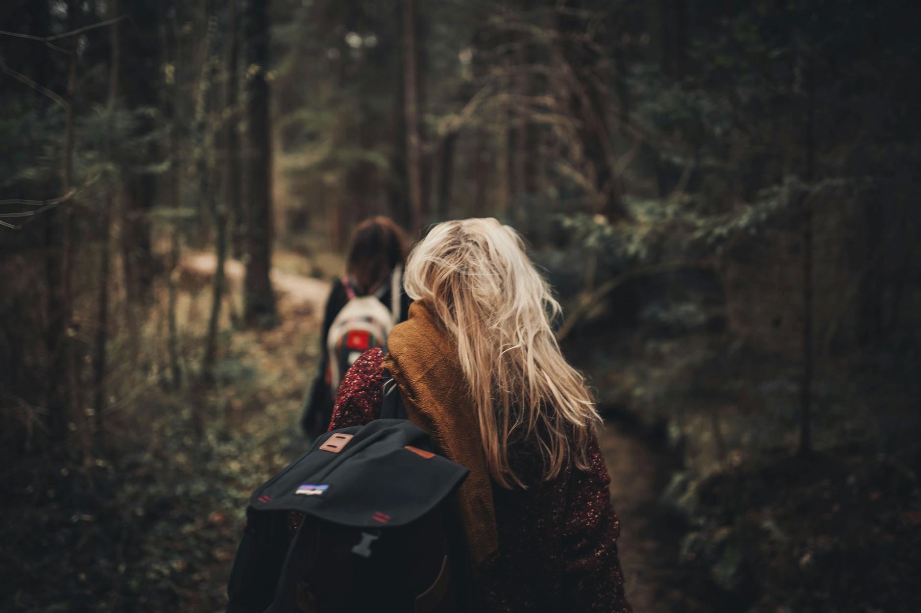 woman in brown scarf surrounded with green trees; bug out bag