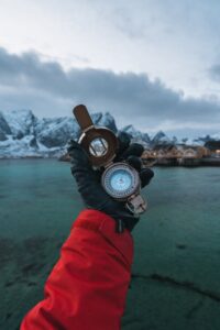 person wearing black leather gloves holding brass colored compass
