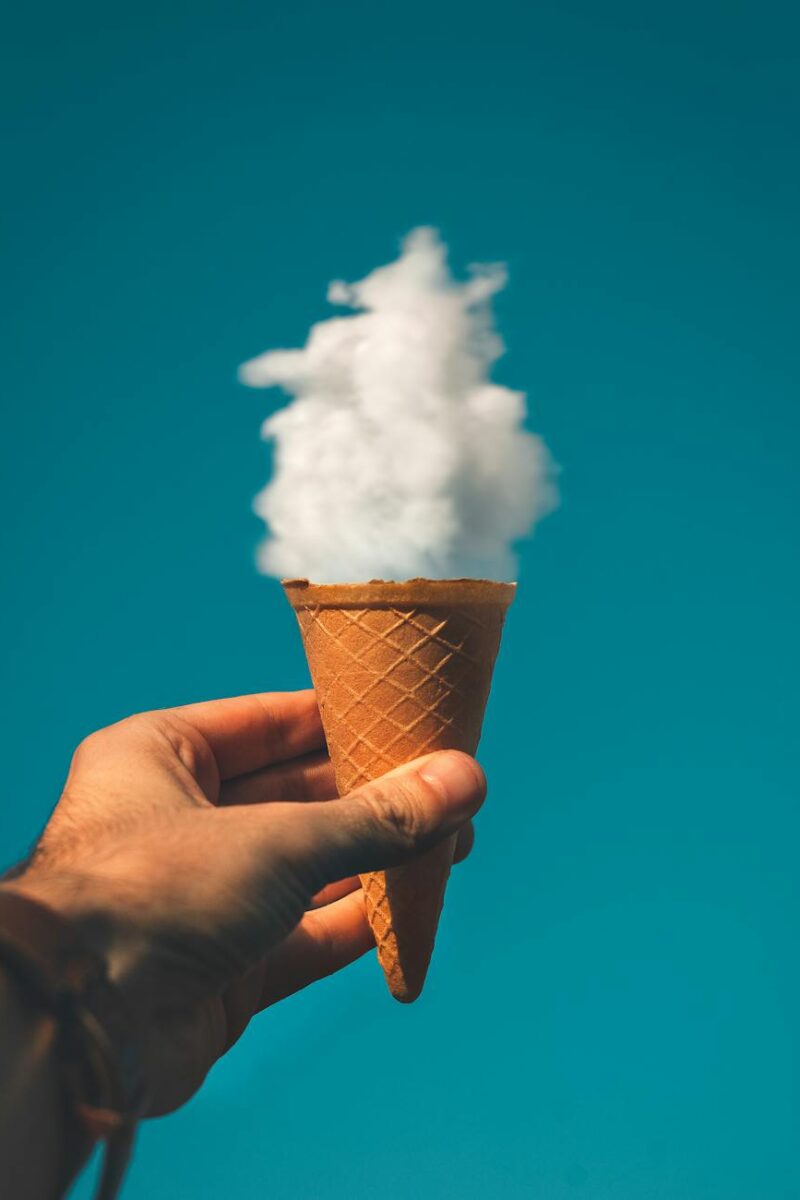 man holding ice cream cone under cloud