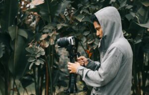 man in hooded jacket holding camera with stablizer
